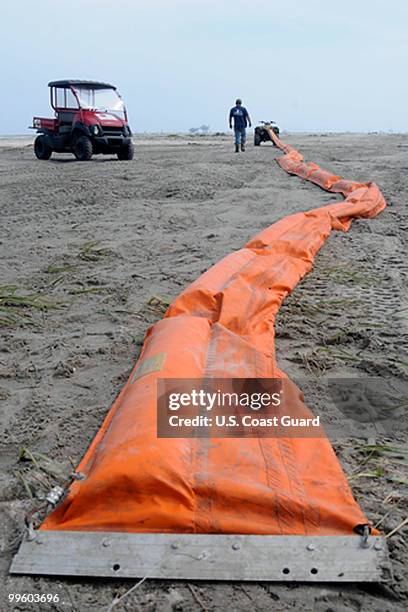 In this handout from the U.S. Coast Guard, Health, Safety and Environment workers place oil containment boom on low areas of the beach that are...