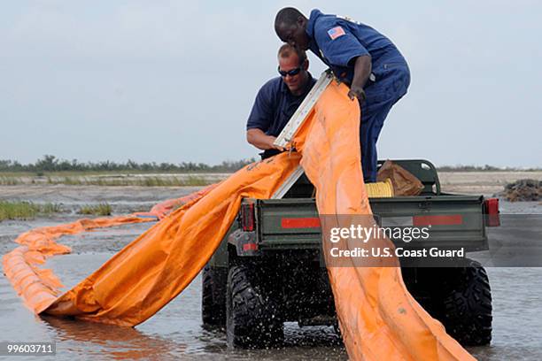 In this handout from the U.S. Coast Guard, Health, Safety and Environment workers place oil containment boom on low areas of the beach that are...