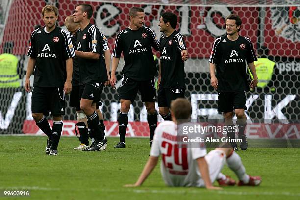 Daniel Brinkmann of Augsburg sits on the pitch as players of Nuernberg celebrate after the Bundesliga play off leg two match between FC Augsburg and...