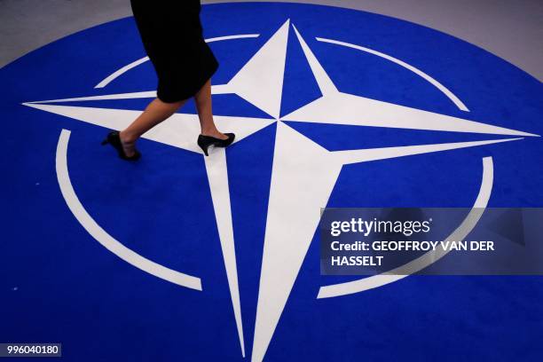 Woman walks across a carpet with the NATO logo ahead of the NATO summit, at the NATO headquarters in Brussels, on July 11, 2018.