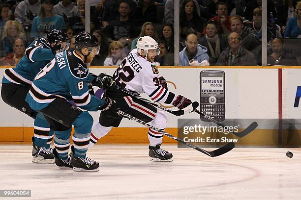 Kris Versteeg of the Chicago Blackhawks goes after the puck alongside Joe Pavelski and Dany Heatley of the San Jose Sharks in the first period in...