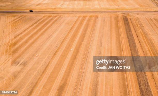 This aerial picture taken in Bennstedt, eastern Germany shows a car standing between harvested cereal fields on July 10, 2018. / Germany OUT