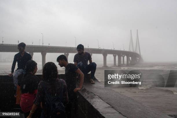 People gather in the rain as the Bandra-World Sea Link bridge stands in the background in the suburb of Bandra in Mumbai, India, on Tuesday, July 10,...