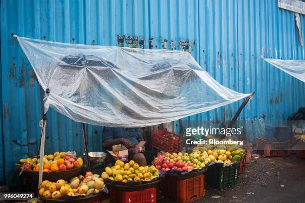 Fruit vendor waits for customers as he sits under a plastic tarp in the suburb of Bandra in Mumbai, India, on Tuesday, July 10, 2018. The monsoon is...