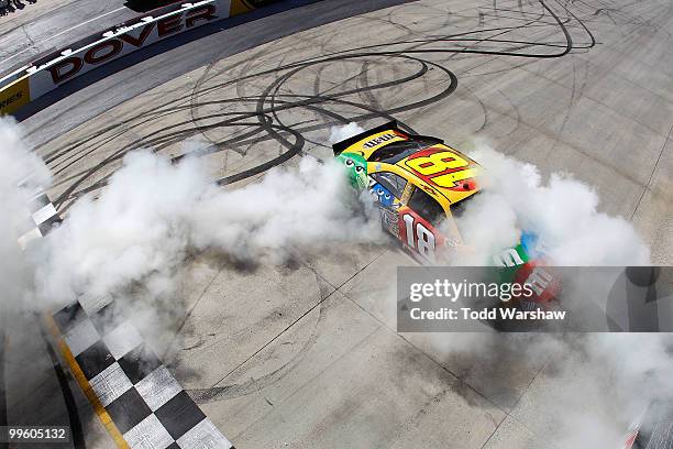 Kyle Busch, driver of the M&M's Toyota, performs a burnout to celebrate after winning the NASCAR Sprint Cup Series Autism Speaks 400 at Dover...