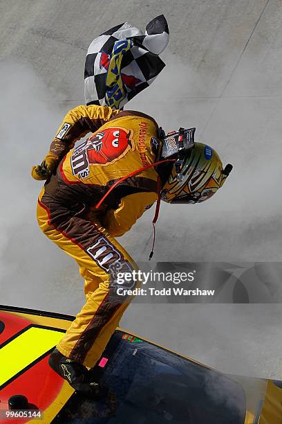 Kyle Busch, driver of the M&M's Toyota, celebrates with the checkered flag after performing a burnout after winning the NASCAR Sprint Cup Series...