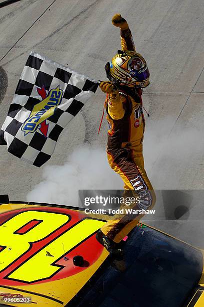 Kyle Busch, driver of the M&M's Toyota, celebrates with the checkered flag after performing a burnout after winning the NASCAR Sprint Cup Series...