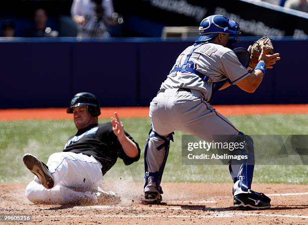 Aaron Hill of the Toronto Blue Jays slides home safe past Matt Treanor of the Texas Rangers during a MLB game at the Rogers Centre May 16, 2010 in...