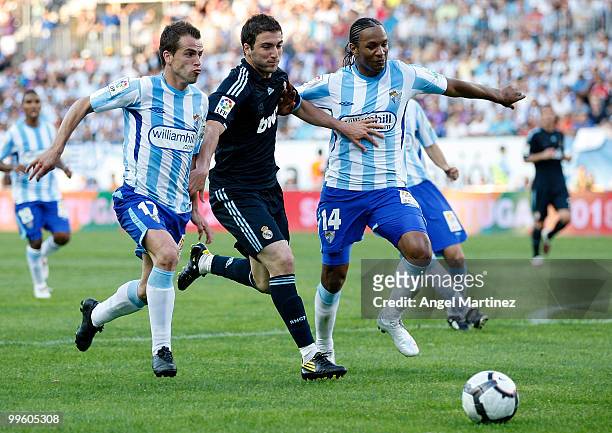 Gonzalo Higuain of Real Madrid fights for the ball with Helder Rosario and Sergio Duda of Malaga during the La Liga match between Malaga and Real...