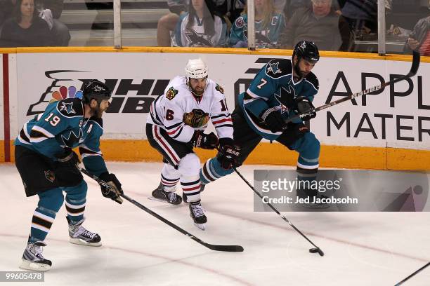 Andrew Ladd of the Chicago Blackhawks moves the puck between Joe Thornton and Niclas Wallin of the San Jose Sharks in the second period in Game One...