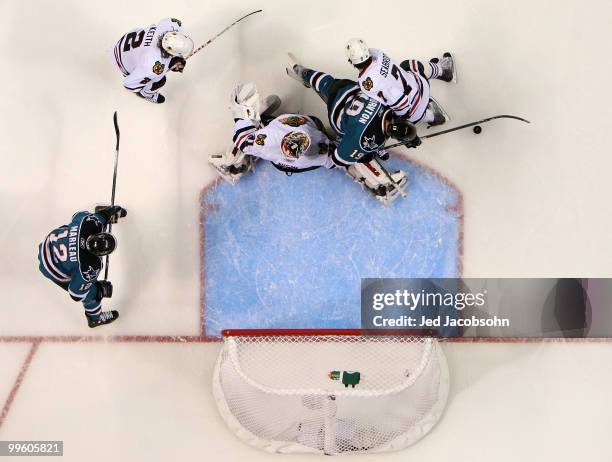 Joe Thornton of the San Jose Sharks attempts a shot as he goes between Brent Seabrook and goaltender Antti Niemi of the Chicago Blackhawks in the...
