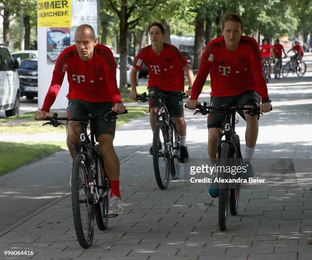 Arjen Robben, Jonas Kehl and goalkeeper Ron-Thorben Hoffmann of FC Bayern Muenchen ride bicycles during a training session near the club's Saebener...