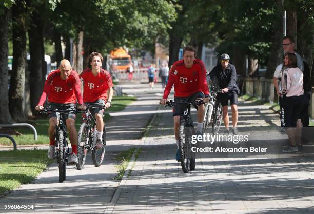 Arjen Robben, Jonas Kehl and goalkeeper Ron-Thorben Hoffmann of FC Bayern Muenchen ride bicycles during a training session near the club's Saebener...