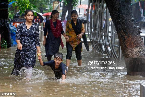 People wade through water-logged roads during heavy rains, on July 10, 2018 in Mumbai, India. Heavy rains across Mumbai city and adjoining areas...