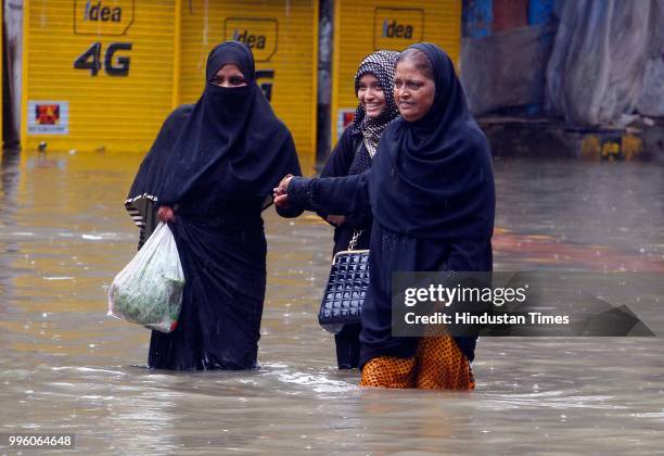 People wade through water-logged roads during heavy rains, on July 10, 2018 in Mumbai, India. Heavy rains across Mumbai city and adjoining areas...