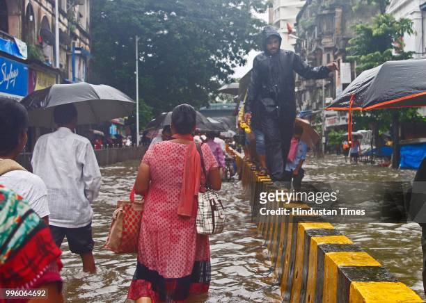 People wade through water-logged roads during heavy rains, on July 10, 2018 in Mumbai, India. Heavy rains across Mumbai city and adjoining areas...