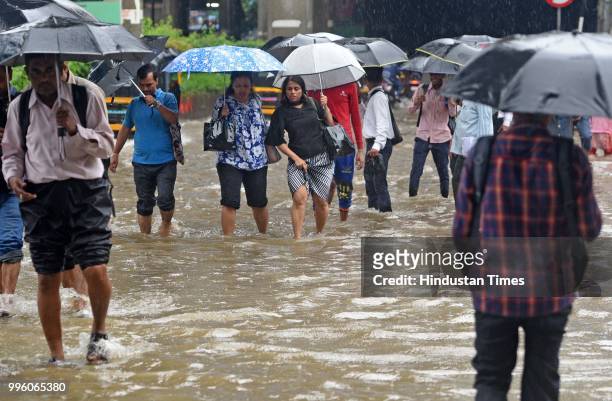 Vehicles and people wade through waterlogged street near WEH metro station at Andhri Kurla Road, on July 10, 2018 in Mumbai, India. Heavy rains...