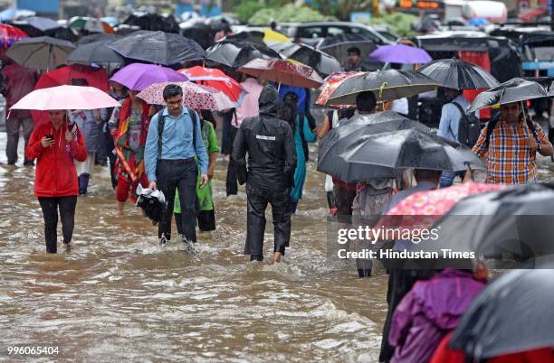 Vehicles and people wade through waterlogged street near WEH metro station at Andhri Kurla Road, on July 10, 2018 in Mumbai, India. Heavy rains...