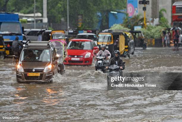 Vehicles and people wade through waterlogged street near WEH metro station at Andhri Kurla Road, on July 10, 2018 in Mumbai, India. Heavy rains...