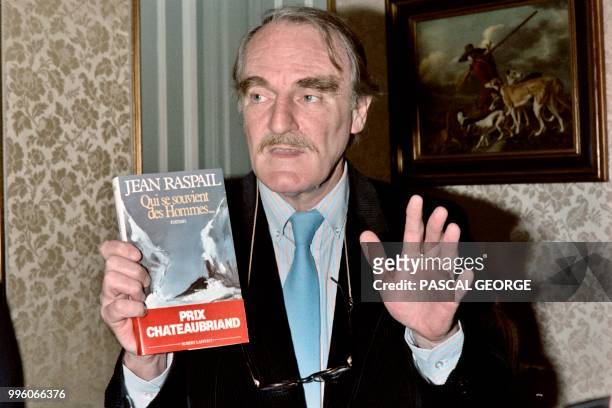 French writer Jean Raspail poses on December 2, 1986 with his book "Qui se souvient des hommes...", "Who Will Remember the People...", awarded by the...