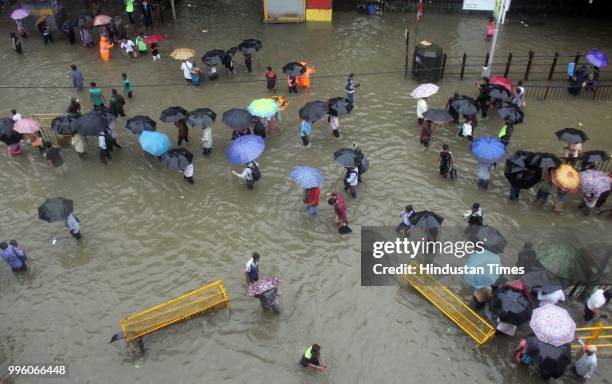 People walk along a flooded street during heavy rain showers, at Parel, on July 10, 2018 in Mumbai, India. Heavy rains across Mumbai city and...