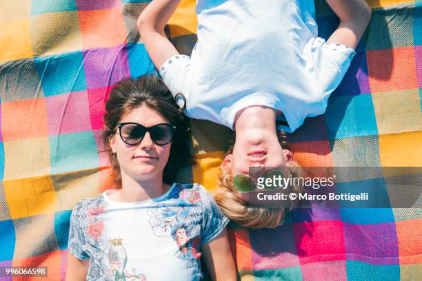 adult woman and her son relaxing on a colorful mat - quirky family stockfoto's en -beelden