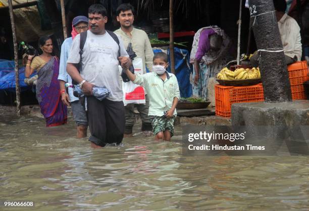 People walk along a flooded street during heavy rain showers, at Parel, on July 10, 2018 in Mumbai, India. Heavy rains across Mumbai city and...