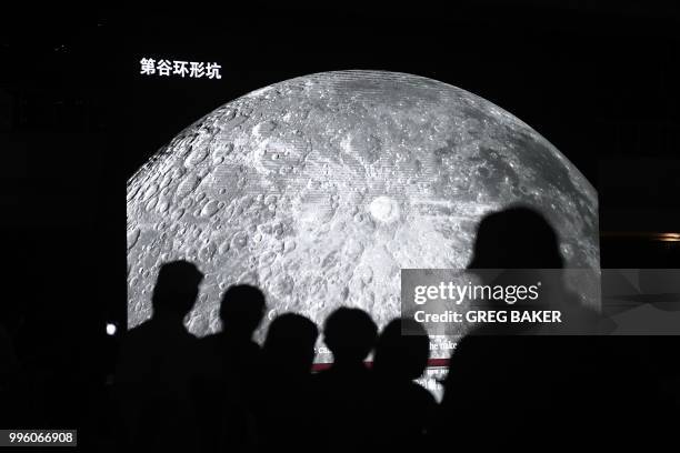 People watch a video presentation about China's moon exploration at an exhibition at the National Aquatics Center, known as the Water Cube, in...