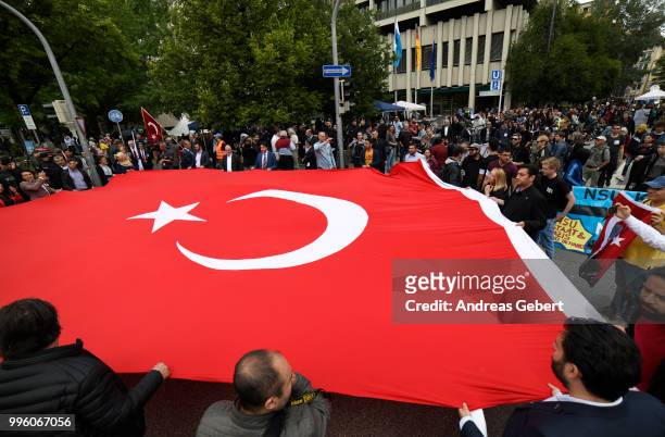 Members of the Turkish community stand in front of the Oberlandesgericht courthouse with a large Turkish flag after judges announced their verdict in...