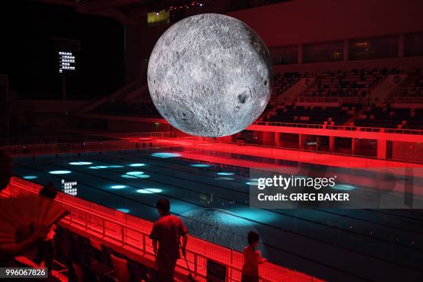 Model of the moon hangs above the Olympic swimming pool at the National Aquatics Center, known as the Water Cube, in Beijing on July 11, 2018. - The...