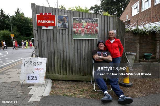 Mr and Mrs Anslow pose in their driveway advertising Parking for £25 along with newspaper clippings of England manager Gareth Southgate and a...