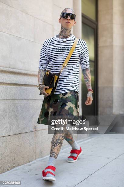 Chris Lavish is seen on the street attending Men's New York Fashion Week wearing Diplomacy shirt, Friedman kilt by Mickey, Moschino glasses, Versace...