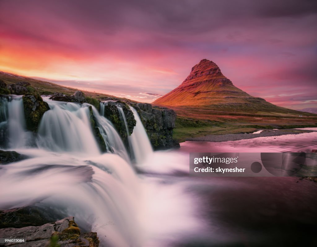 Kirkjufellsfoss waterval met Kirkjufell berg op de achtergrond bij zonsondergang.
