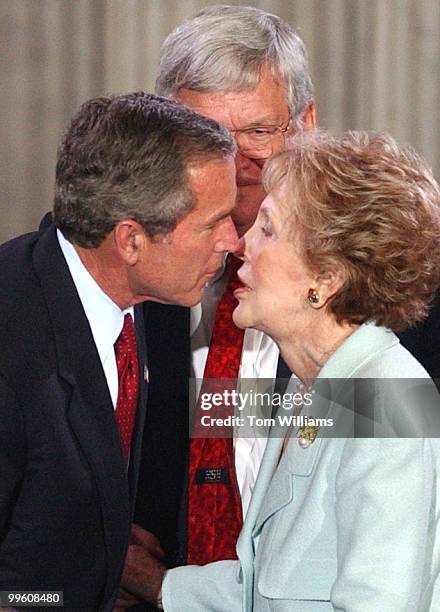 President George W. Bush, gives a kiss to Nancy Reagan as Speaker Dennis Hastert, R-Ill., looks on at a ceremony in the Rotunda of the Capitol...