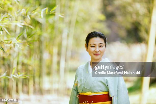 asian woman wearing a kimono walking in bamboo grove - masafumi nakanishi imagens e fotografias de stock
