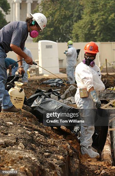 Reyes Martinez, left, sprays off a worker in a ditch with asbestos tainted pipes on the construction site for the Capitol Visitor Center, on the East...