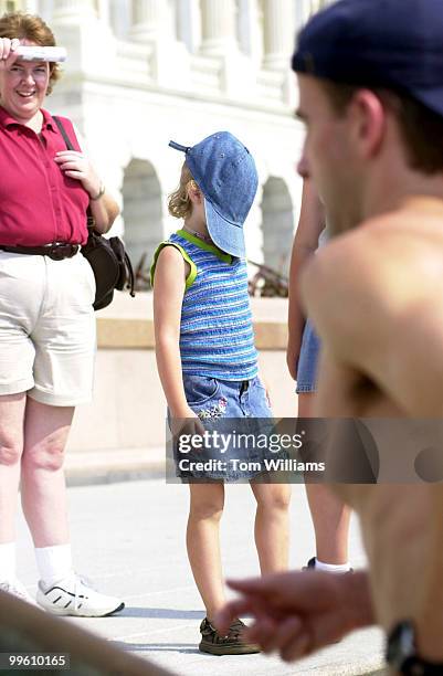 Five year old Catlyn Bonz of Dubuque, Iowa, pulls a hat over her face to shield the sun on the West Front, Thursday afternoon.