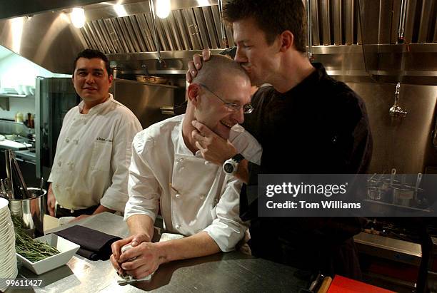 Chef Bart Vandaele kisses cook Benjamin Clerici at Belga Cafe on 8th St., SE. Cook Christian Villalta looks on.
