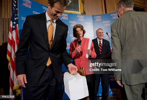 Sen. John Thune, R-S.D., tests the weight of the 2000 page health care bill after a news conference that some senators say would "raise taxes, raises...