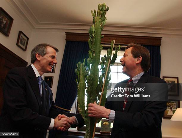 Rep. Earl Pomeroy, D-N.D., right, receives a cactus from Rep. Rob Portman, R-Ohio, as part of a tradition in Congress. Passed down from member to...