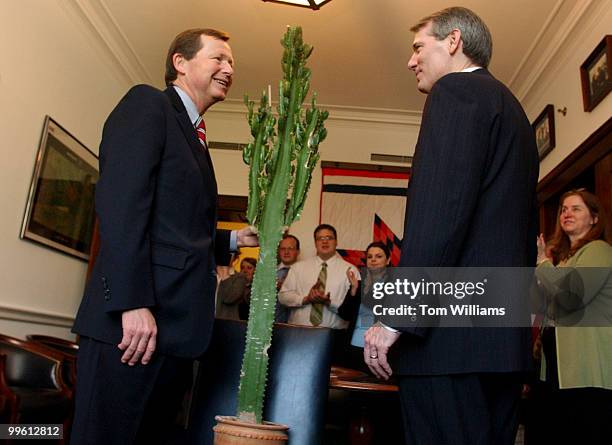 Rep. Earl Pomeroy, D-N.D., left, receives a cactus from Rep. Rob Portman, R-Ohio, as part of a tradition in Congress. Passed down from member to...