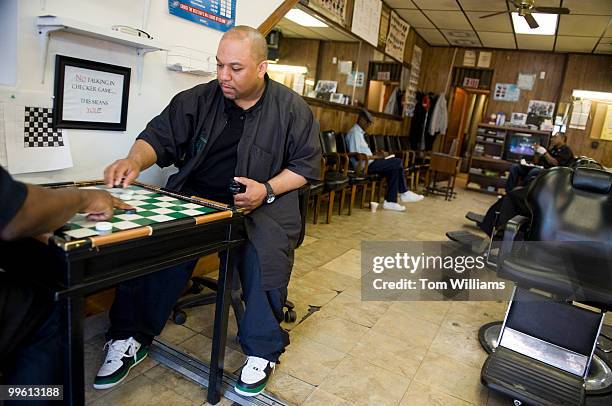 Robbie Mason, co-owner of Mason's Barber Shop, plays checkers during a slow day in the shop, April 5, 2010.