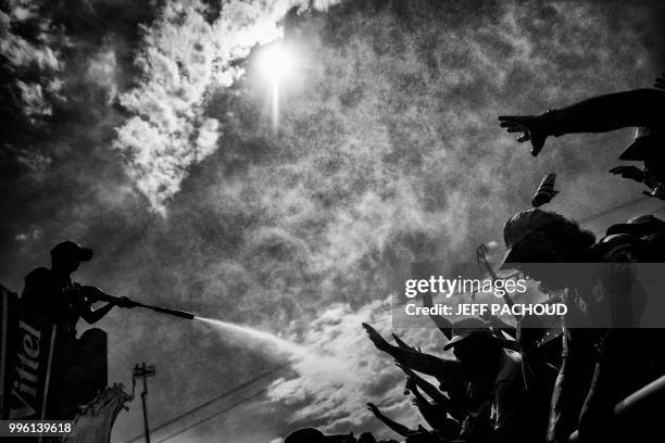 Woman form the publicity caravan sprays refreshing water on spectators waiting at the finish line to watch the arrival of the fourth stage of the...