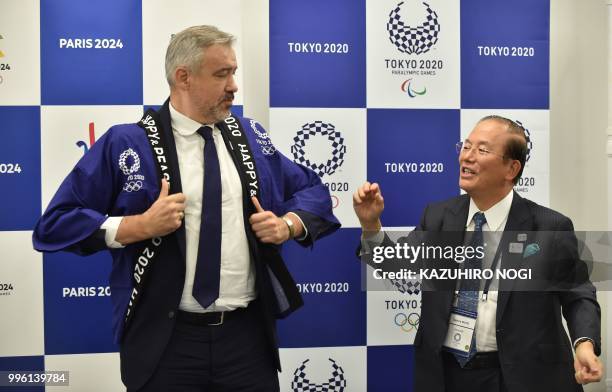 Paris 2024 Director General Etienne Thobois wears a traditional Japanese happi coat presented by Tokyo 2020 CEO Toshiro Muto after a signing ceremony...