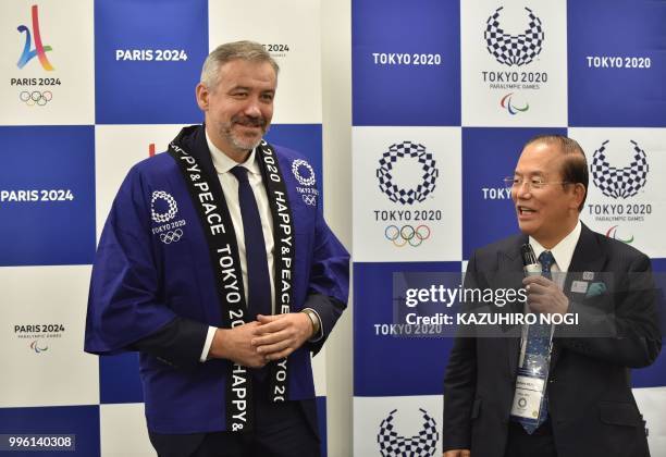 Paris 2024 Director General Etienne Thobois wears a traditional Japanese happi coat presented by Tokyo 2020 CEO Toshiro Muto after a signing ceremony...