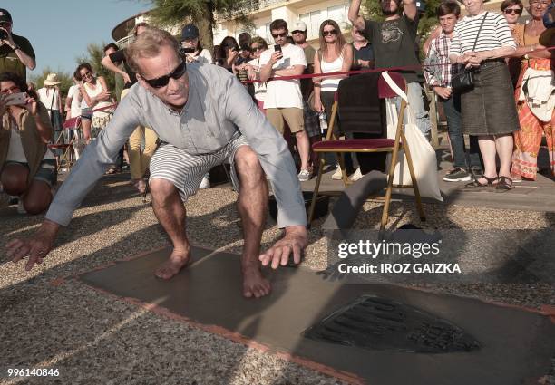 Surfer Tom Curren leaves his footprint cement slab as he takes part in the inauguration of the Anglet Surf Avenue with other surfers from all over...