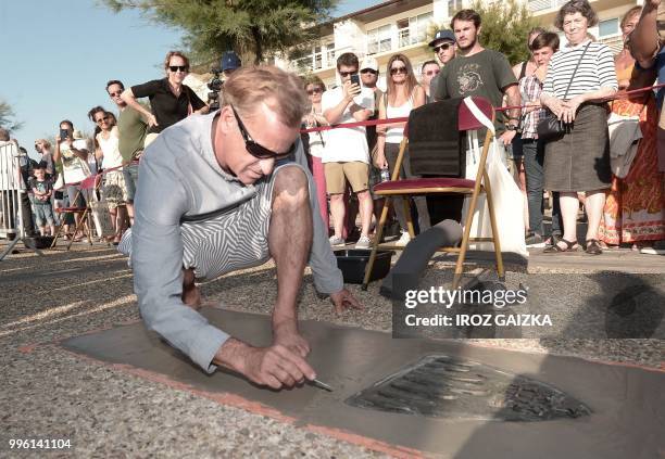 Surfer Tom Curren leaves his footprint cement slab as he takes part in the inauguration of the Anglet Surf Avenue with other surfers from all over...