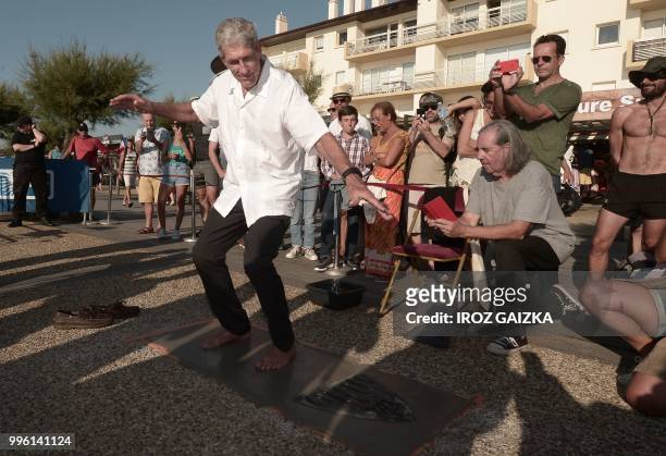 Australian surfer Nat Young leaves his footprint cement slab as he takes part in the inauguration of the Anglet Surf Avenue with other surfers from...