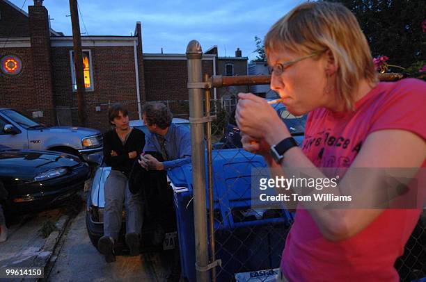 Lisa Janssen lights a cigarette while Jay Marx and Kathleen Gabel hang out on a car, at the Code Pink house on 5th street, NE.