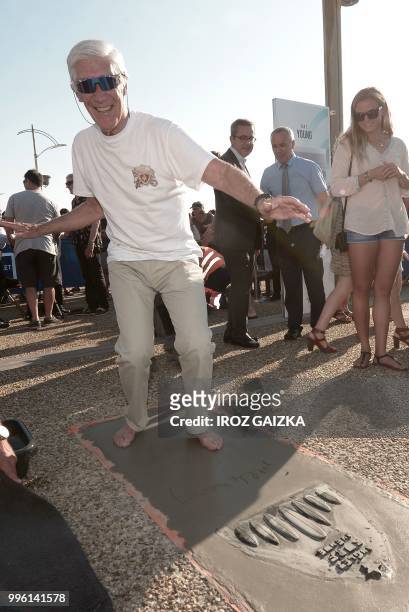 French surfer Joel De Rosnay leaves his footprint cement slab as he takes part in the inauguration of the Anglet Surf Avenue with other surfers from...